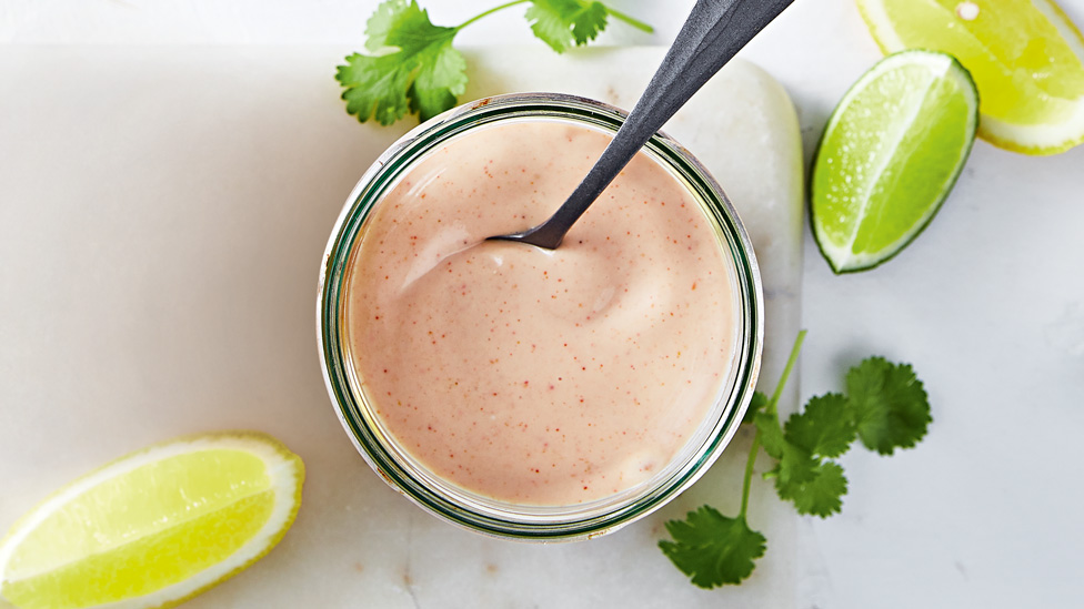 Creamy classic seafood sauce in a serving dish with lime and lemon wedges on the side.