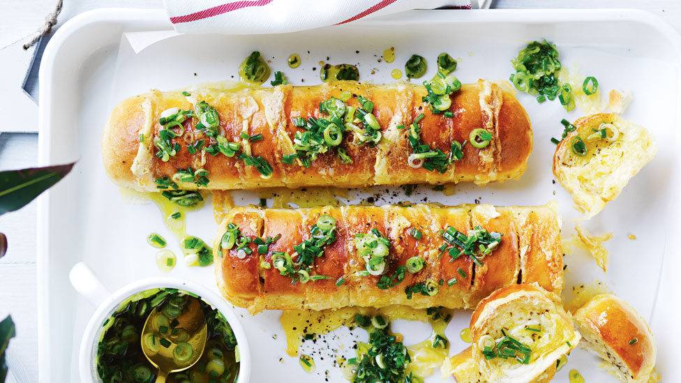 Two garlic baguette with brie on a baking tray