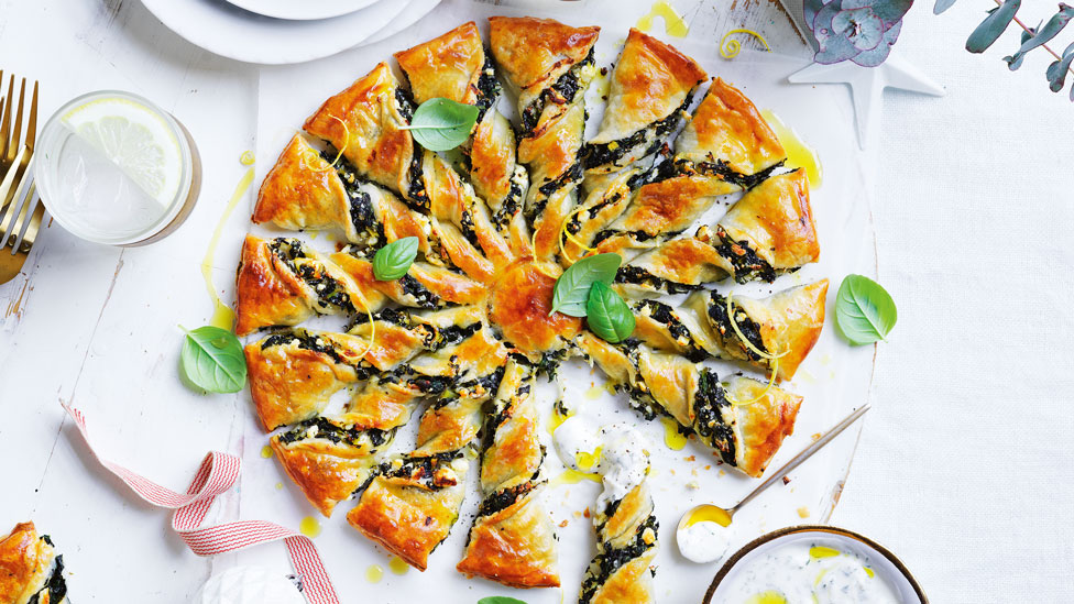 Herb and fetta sunburst tart cut into wedges and served with lemony yoghurt