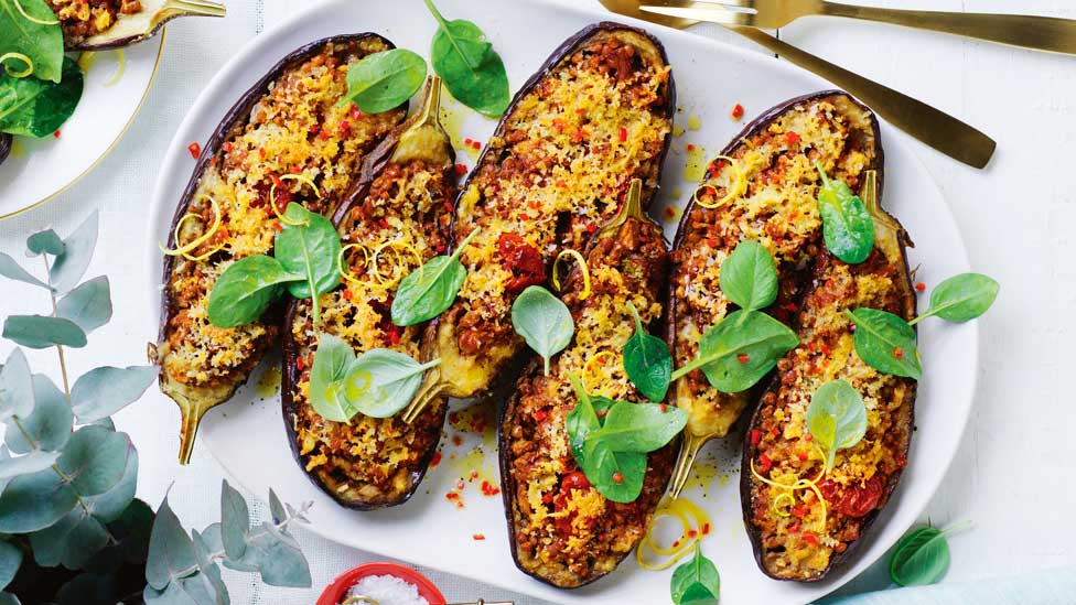 Six lentil-stuffed eggplants on a baking tray