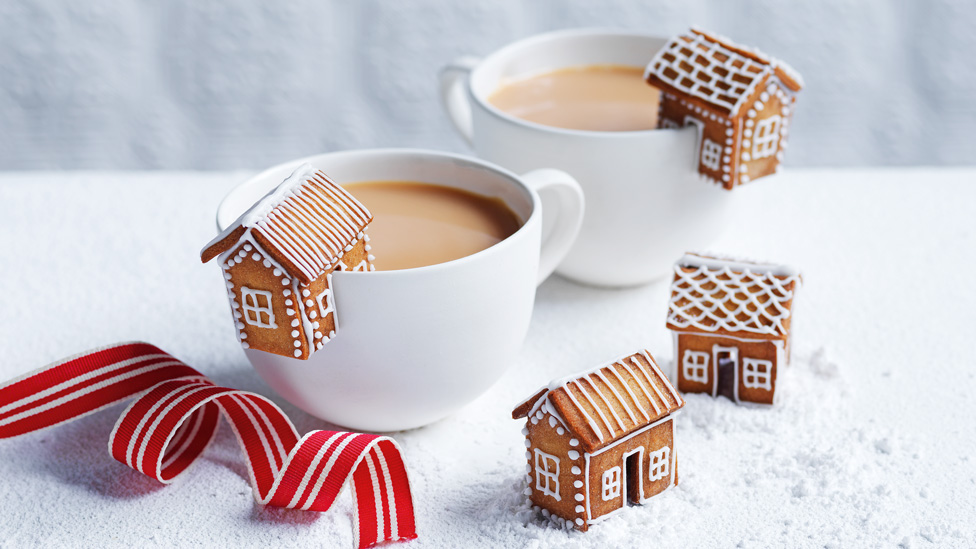 Four mini gingerbread houses with two cups of coffee