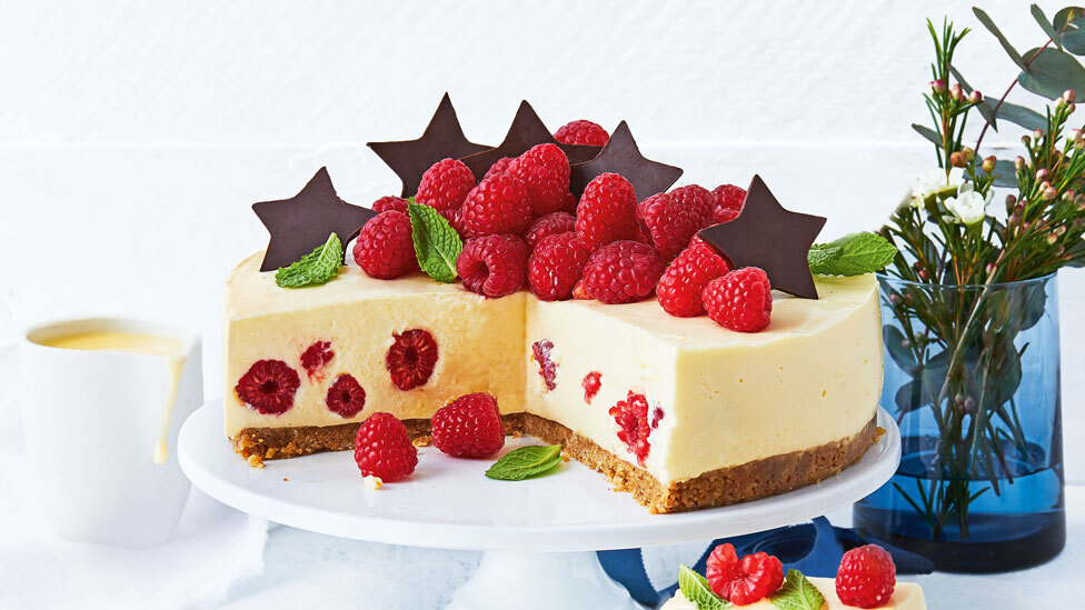 No-bake raspberry and brandy custard cheesecake garnished with fresh raspberries and chocolate stars.