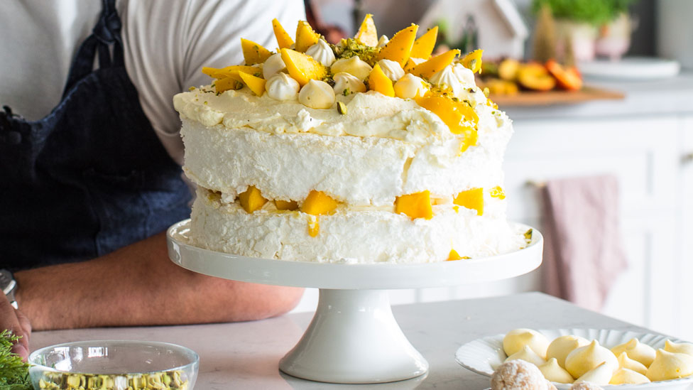 A double-decker pavlova decorated with mango and pistachio