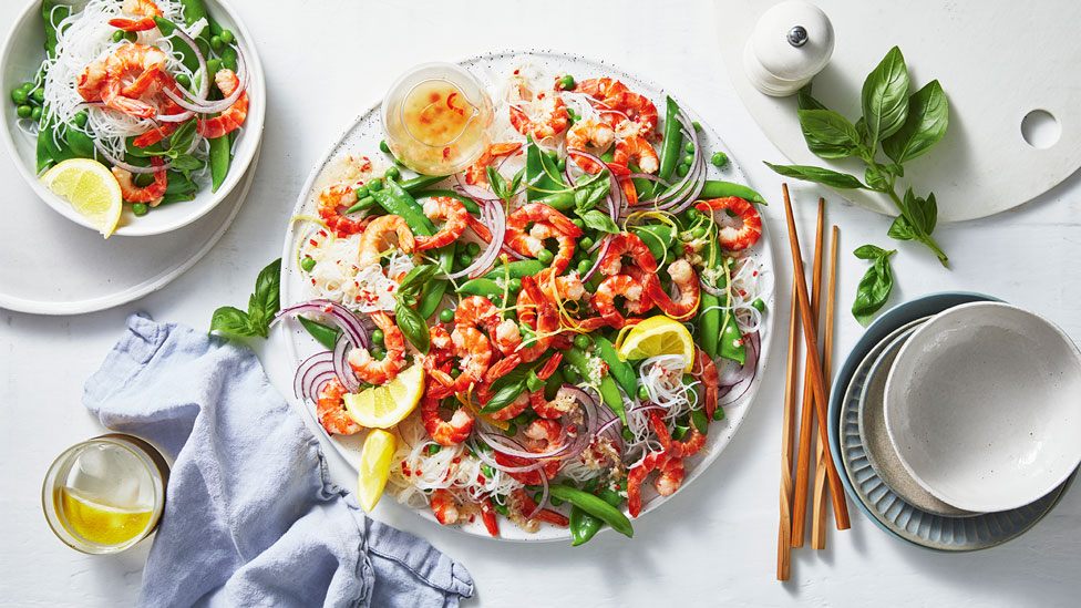 Prawn and mixed pea noodle salad with lemon wedges