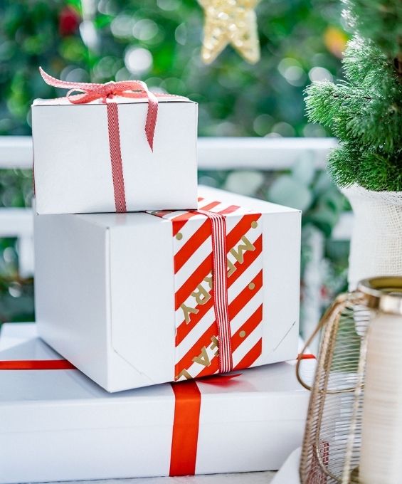 3 stacked christmas presented with white paper and red striped ribbons