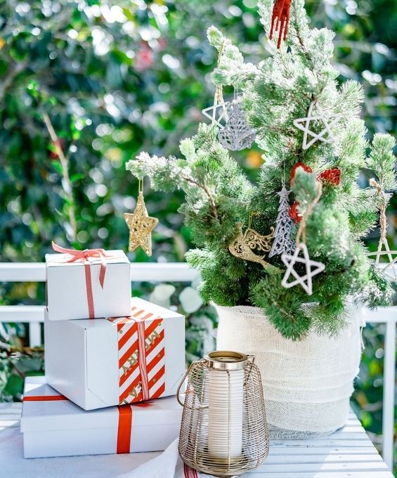 3 stacked christmas presents next to a natural christmas tree with loose and simple decorations