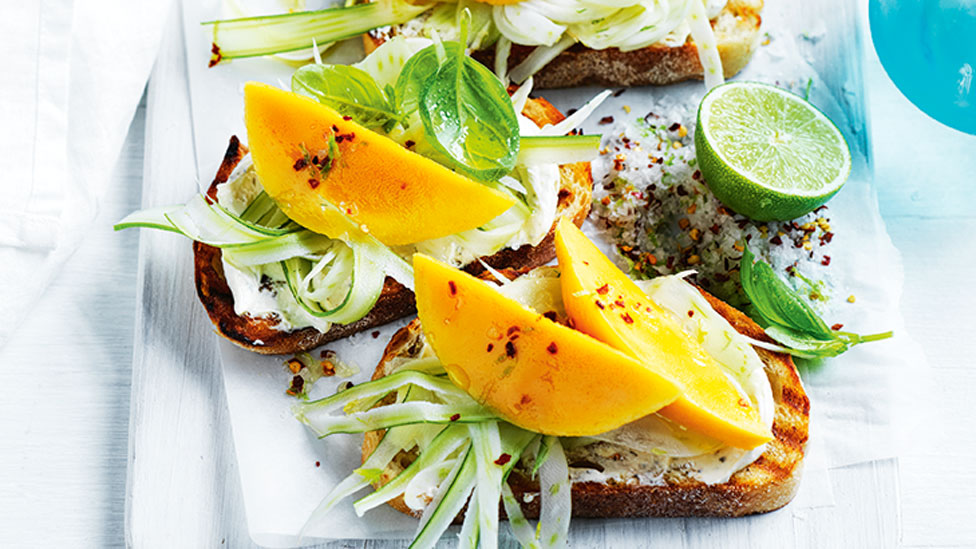 Two pieces of crostini topped with mango and pickled fennel