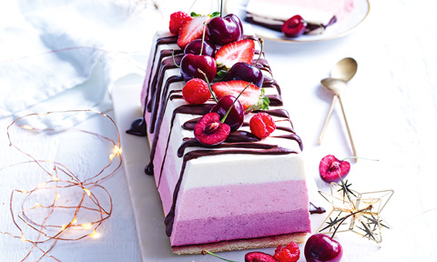 Frozen mousse cake topped with cherries and strawberries