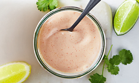 Creamy classic seafood sauce in a serving dish with lime and lemon wedges on the side.