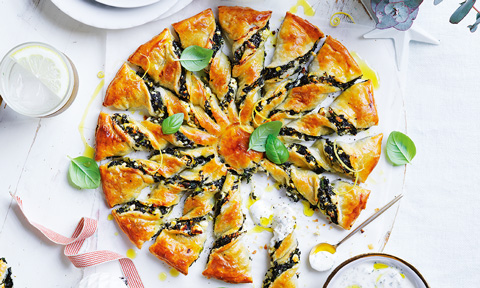 Asorted slices of herb and fetta sunburst tart, garnished with basil leaves.