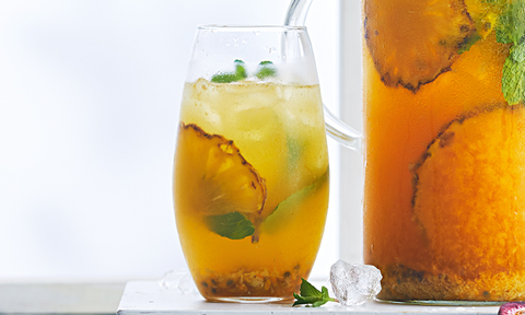 Two cups of pineapple, passionfruit and coconut punch with mint sprigs