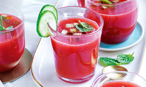 A tomato and watermelon gazpacho shot decorated with cucumber slices.