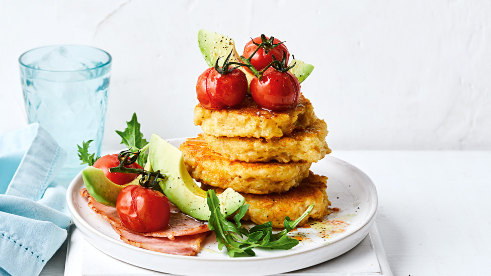 A stack of cauliflower and buttermil fritters with avocado and cherry tomatoes