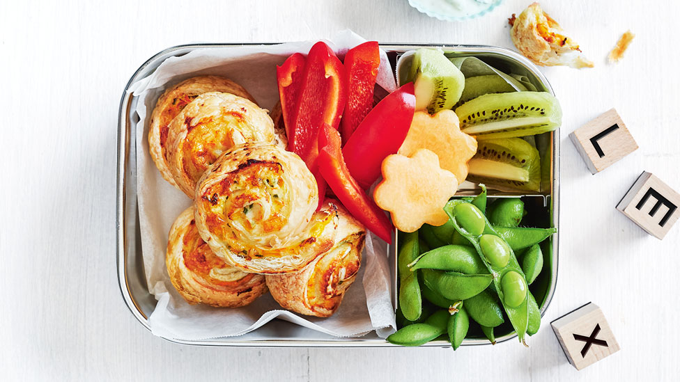Chicken and corn pinwheels in a lunchbox next to capsicum and kiwi fruit