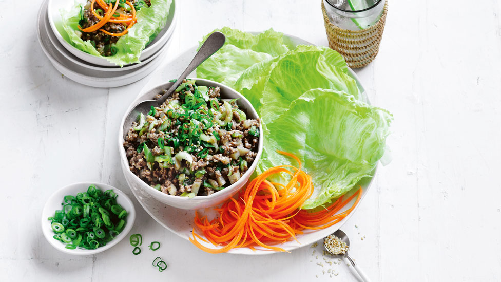 A bowl of spiced pork served with iceberg lettuce, carrot and dressing