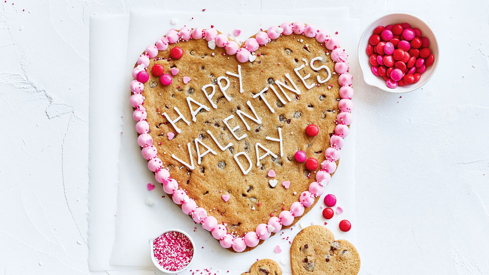 A heart shape Valentines cookie with strawberry frosting and M&M