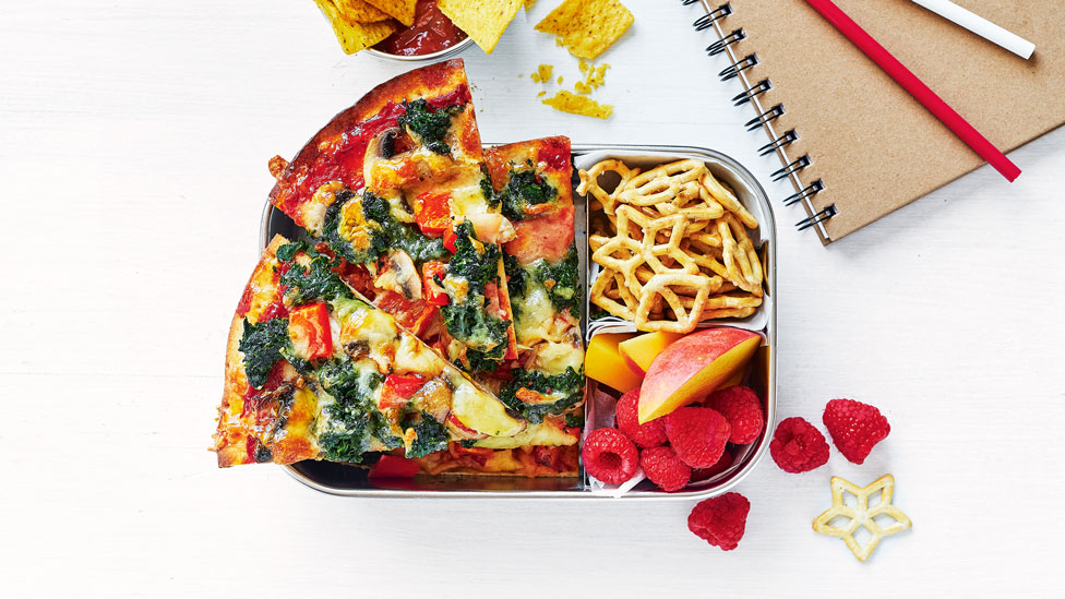 3 slices of spinach and mushroom pizza in a lunch box with some fruit