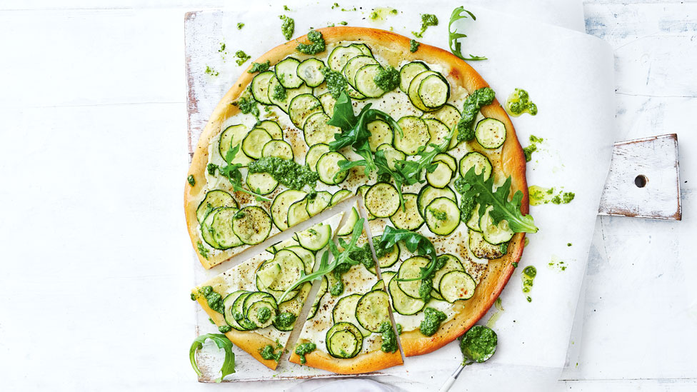 A pizza topped with sliced zucchini and pesto