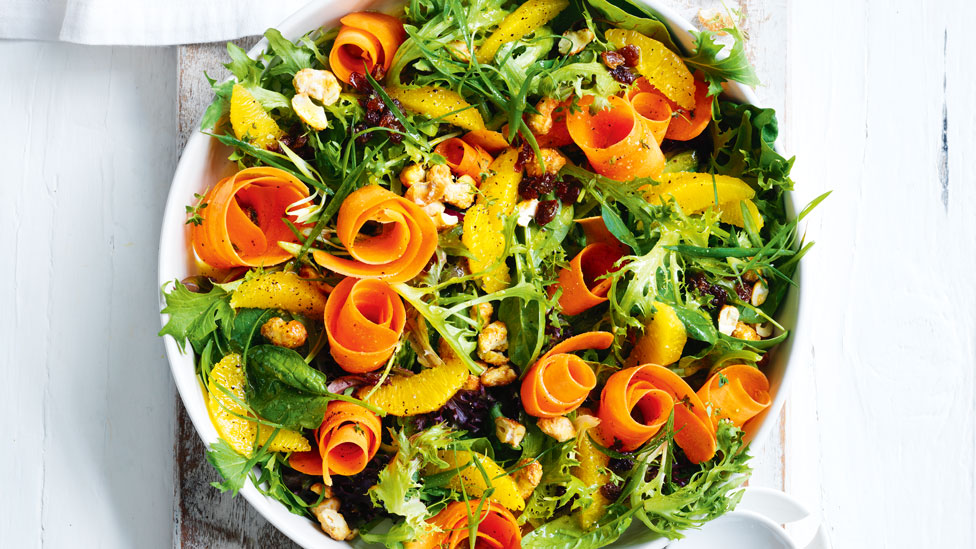 Salad leaves with carrot ribbons, orange and chopped cashews