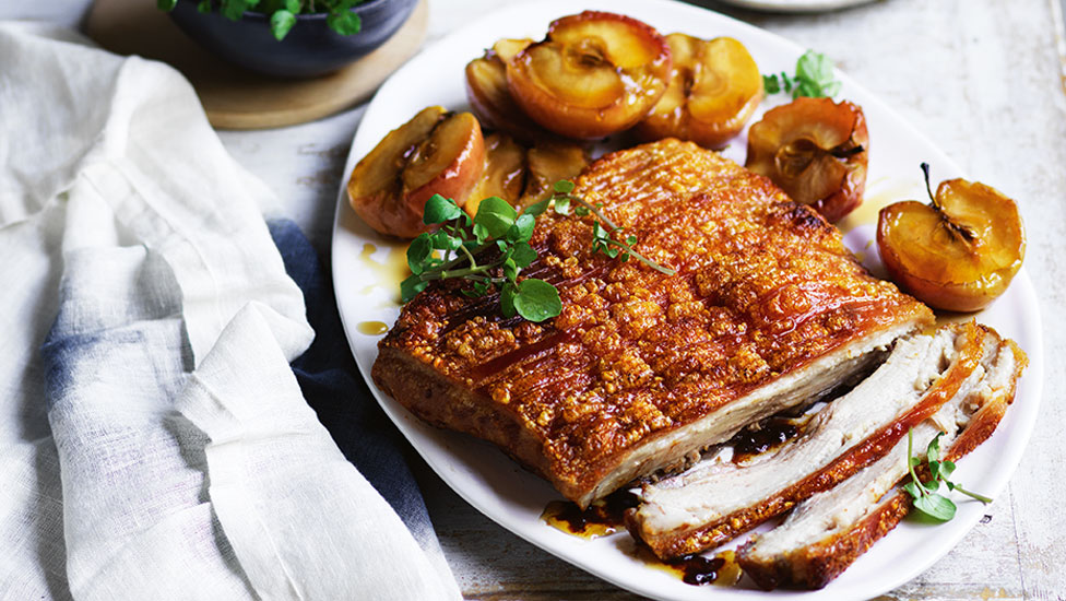 Thickly cut crackling pork belly with roasted apples cut in half