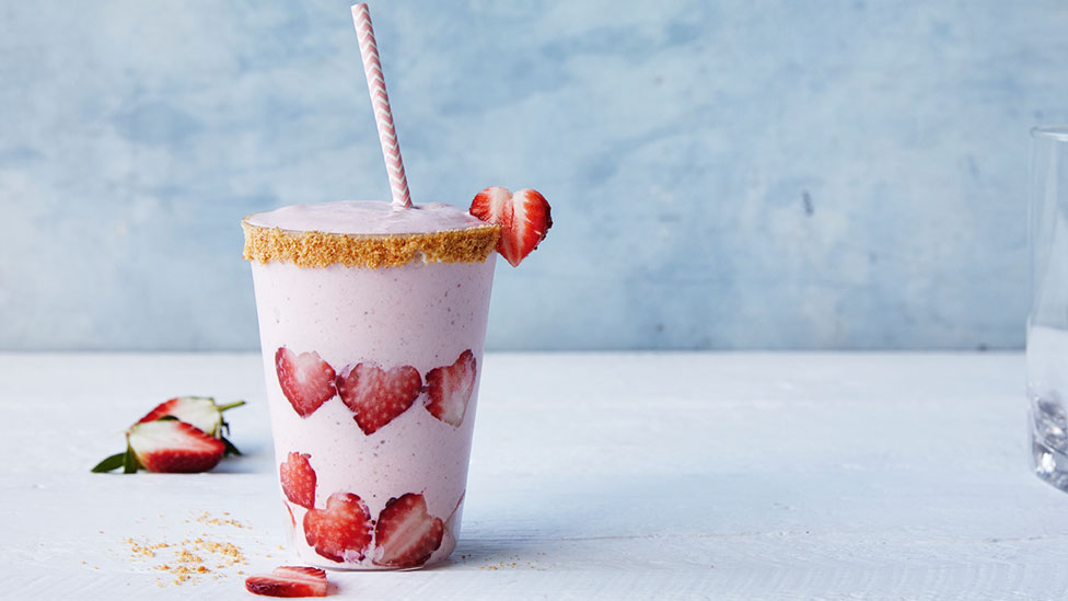 A cup of cheesecake smoothie decorated with heart-shaped strawberries