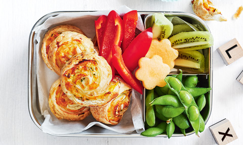 Chicken and corn pinwheels in a lunchbox next to capsicum and kiwi fruit