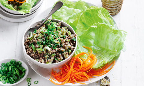 A bowl of spiced pork served with iceberg lettuce, carrot and dressing