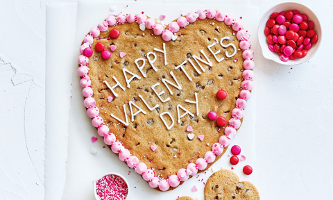 A heart shape Valentines cookie with strawberry frosting and M&M