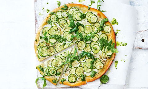 A pizza topped with sliced zucchini and pesto