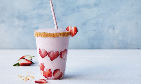 A cup of cheesecake smoothie decorated with heart-shaped strawberries