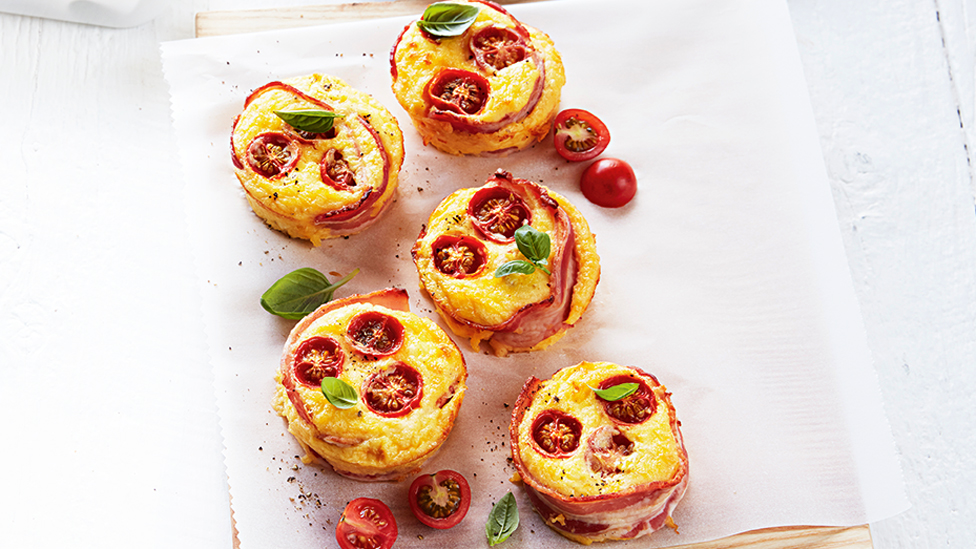 Five bacon and egg quiches with roasted tomatoes and basil on top