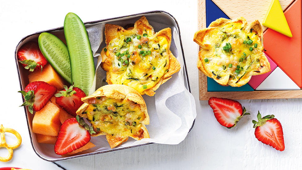 Mini bread quiches served in a lunch box with fresh fruit and vegetables