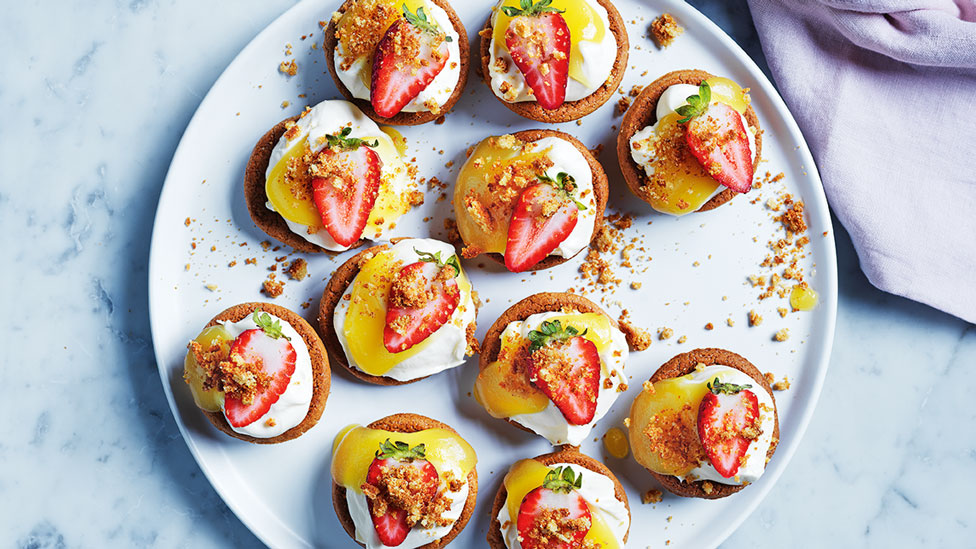 Mini cheesecake tarts served on a platter with strawberries on top