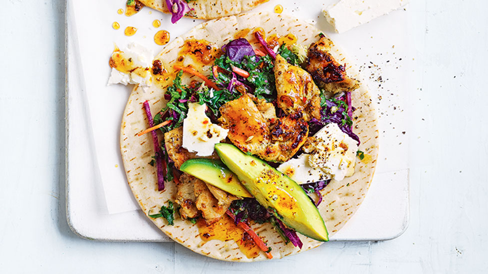 Chicken served on top of a gyros wrap with kaleslaw, avocado and yoghurt