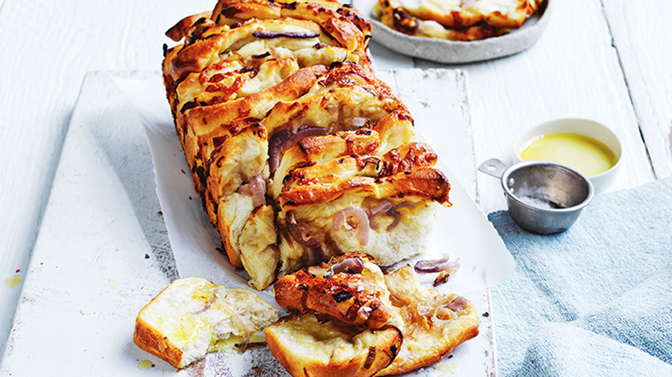 Whole loaf of cheesy onion pull-apart with dipping sauce on the side