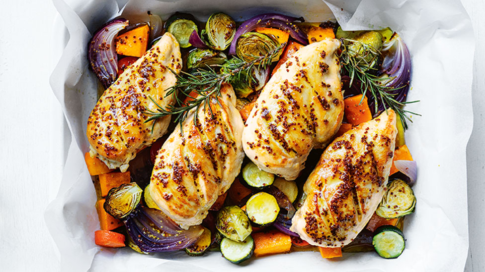 4 chicken breasts served on top of roasted veggies in a baking tray