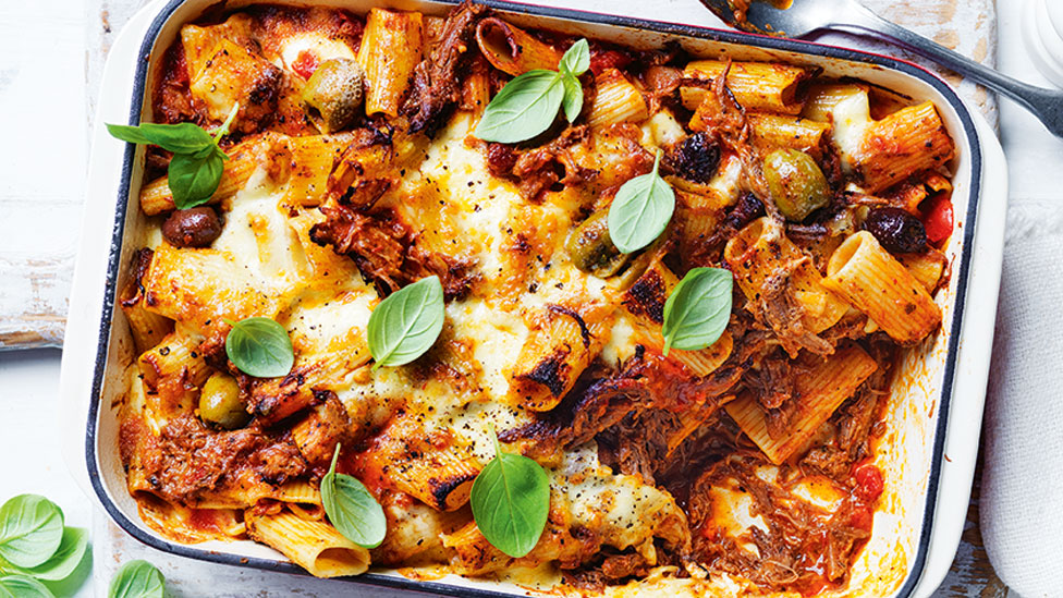 Beef ragu bake in a baking dish with basil on top