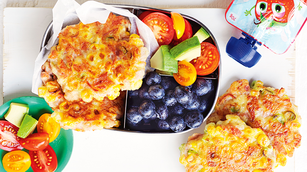 Gluten-free ham and corn fritters served in a lunch box with fresh fruit