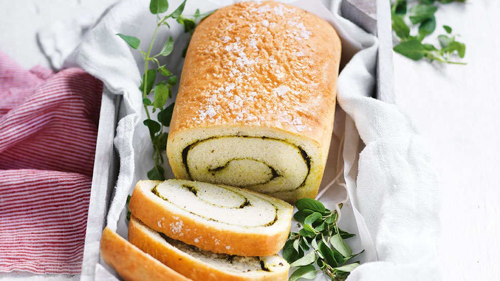 Whole loaf of herb swirl bread served on a chopping board