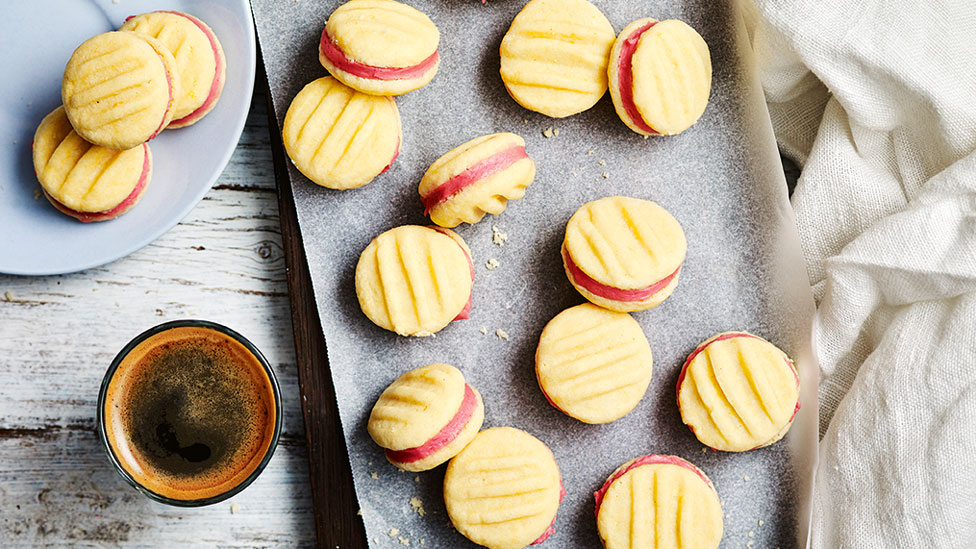 Melting moments served on a chopping board with a cup of coffee on the side