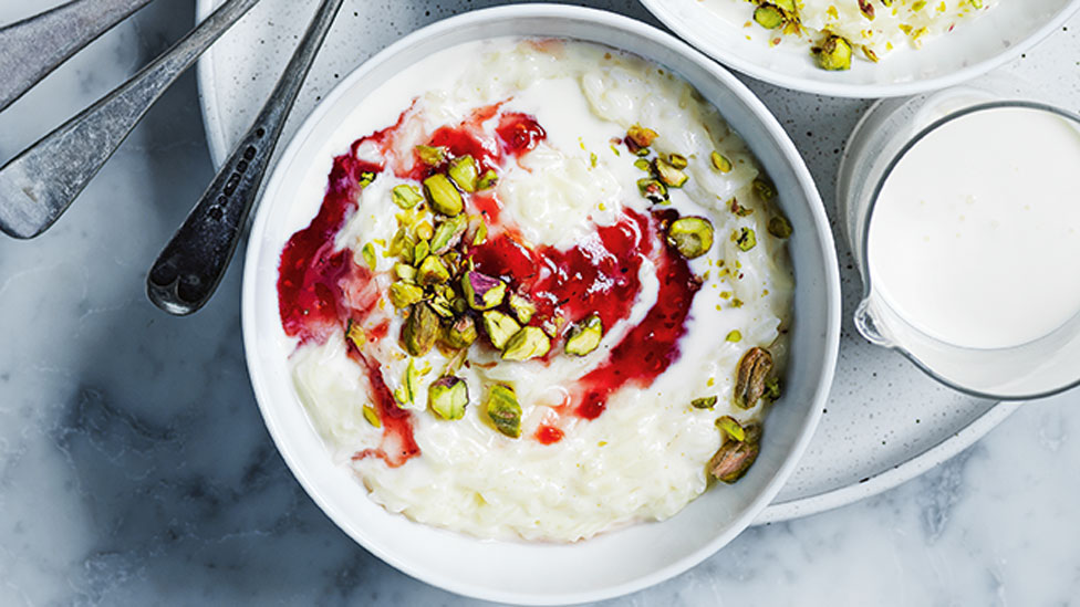 Rice pudding in a bowl with berry compote and pistachios