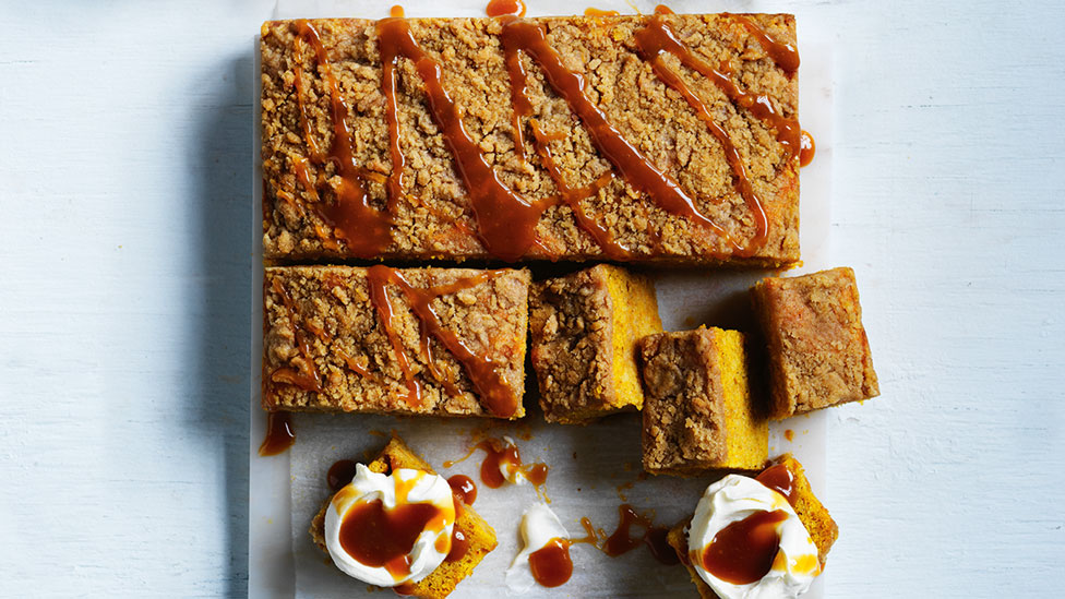Spiced pumpkin with streusel topping and caramel sauce with five slices cut away and served with cream