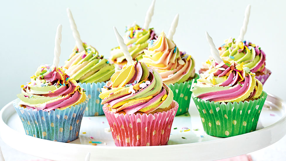 Seven unicorn cupcakes served on a cake stand