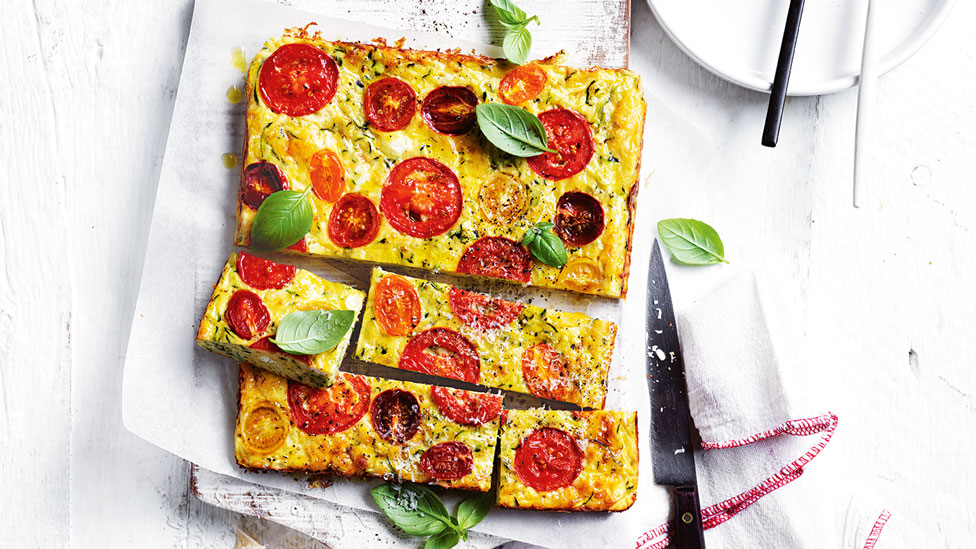 Cheese, tomato and zucchini slice cut in four sections and served on baking paper