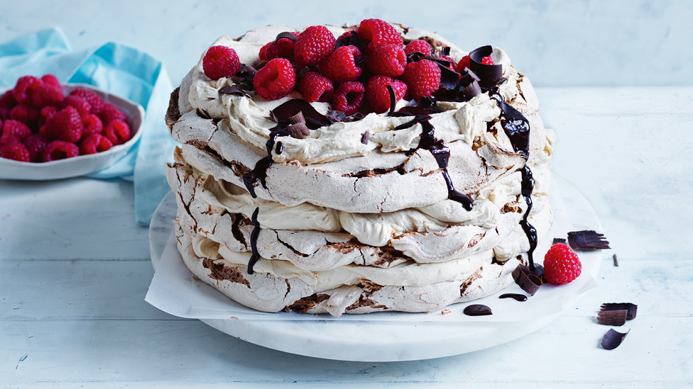 Whole coffee meringue torte with melted chocolate and raspberries on top