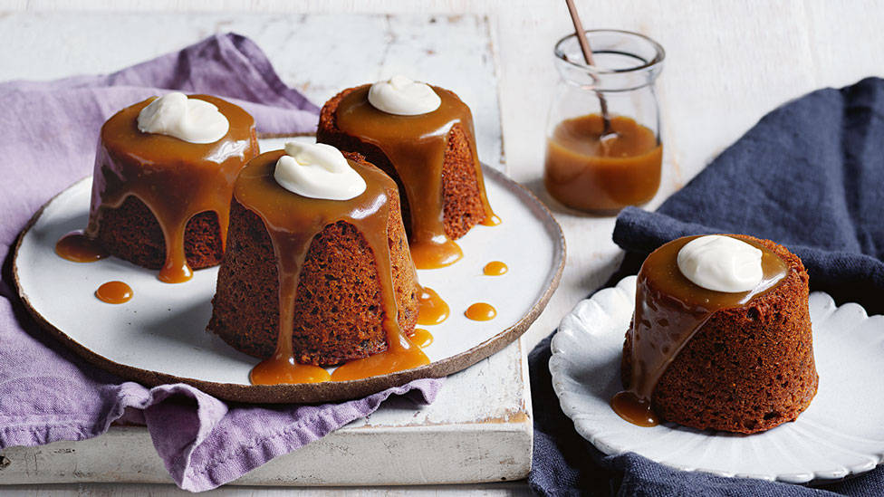 4 small fig and date puddings with butterscotch sauce and cream on top