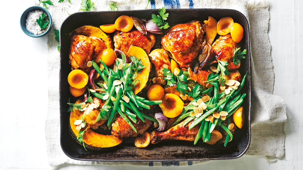 Chicken, apricot and garlic in a baking tray topped with green beans and flaked almonds