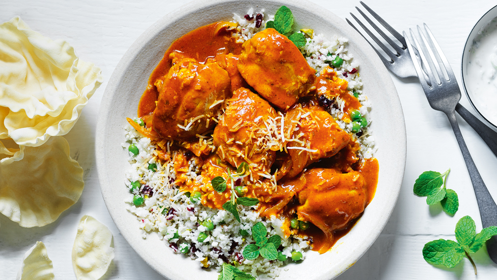 Butter chicken served on top of cauliflower rice with mint as a garnish