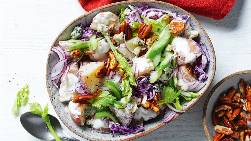 Red cabbage, potatoes, celery and walnut salad served in a bowl with walnuts on the side