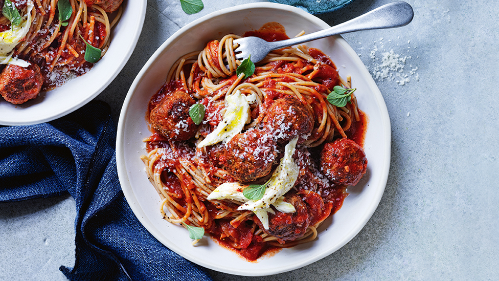 Spaghetti meatballs served in a bowl with basil and parmesan cheese on top